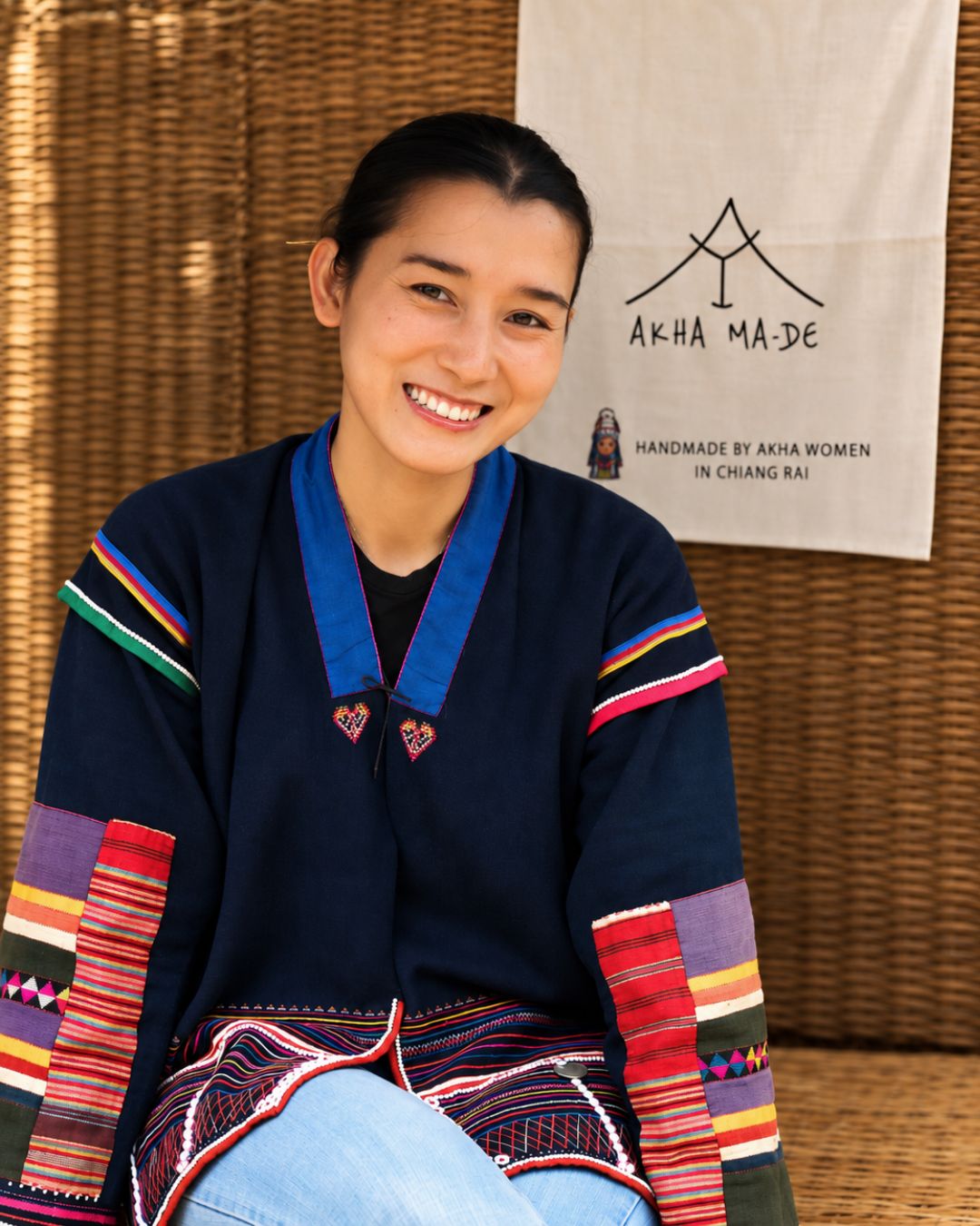 Nichanan A-Ngi wearing Akha clothing beside the Akha Ma-De banner